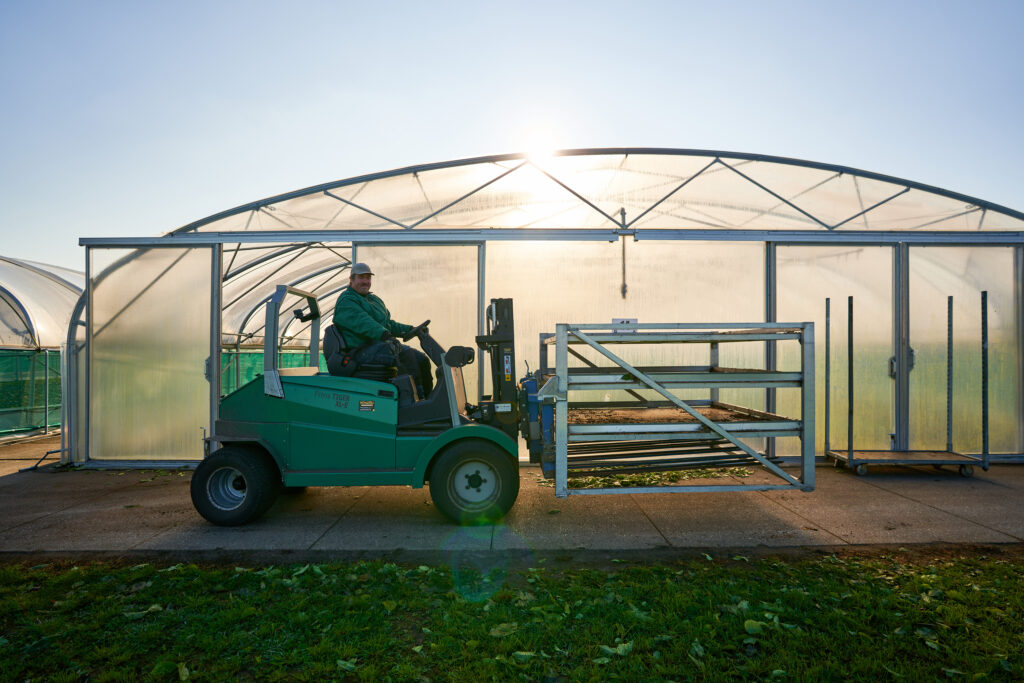 Ergon Kwekerij-medewerker zit op een heftruck die voor de planttunnels stilstaat.