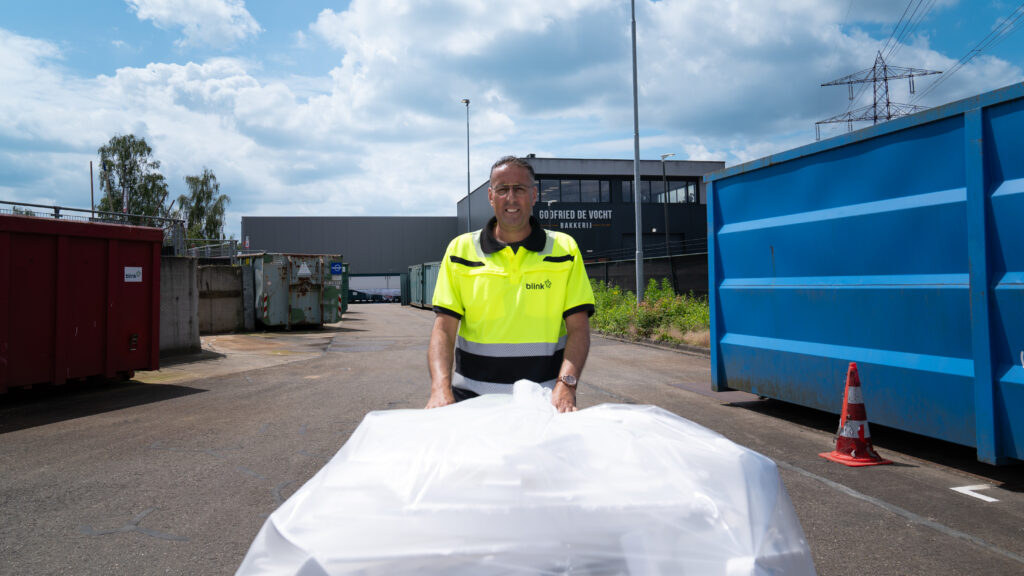 Een medewerker van de milieustraat rijdt met een kar vol spullen over de milieustraat.