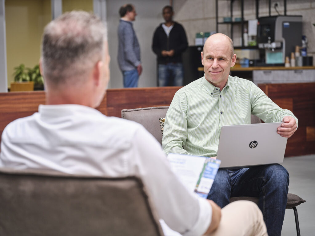 Een gesprek tussen twee mensen, zittend en met een laptop op schoot.