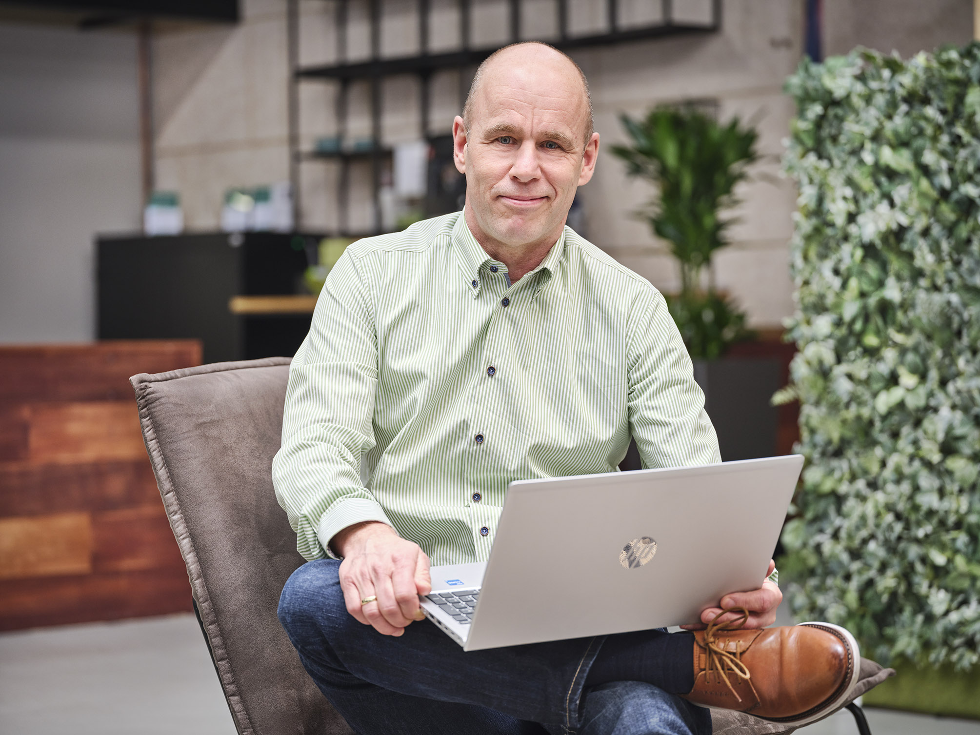 Een Accountmanager zit op een stoel met zijn laptop op schoot.