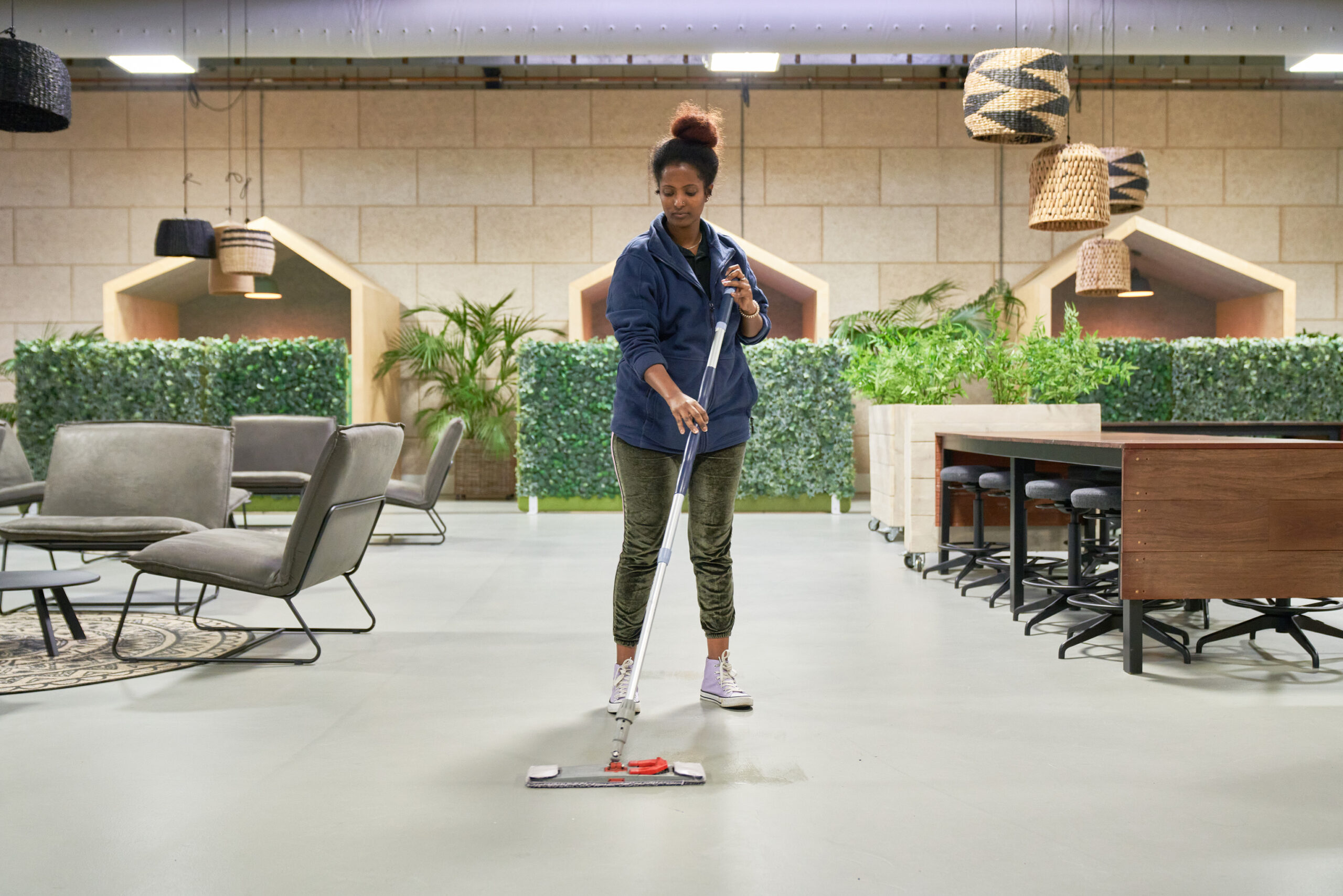 Een medewerker van Ergon Facilitair dweilt de vloer van een kantooromgeving.