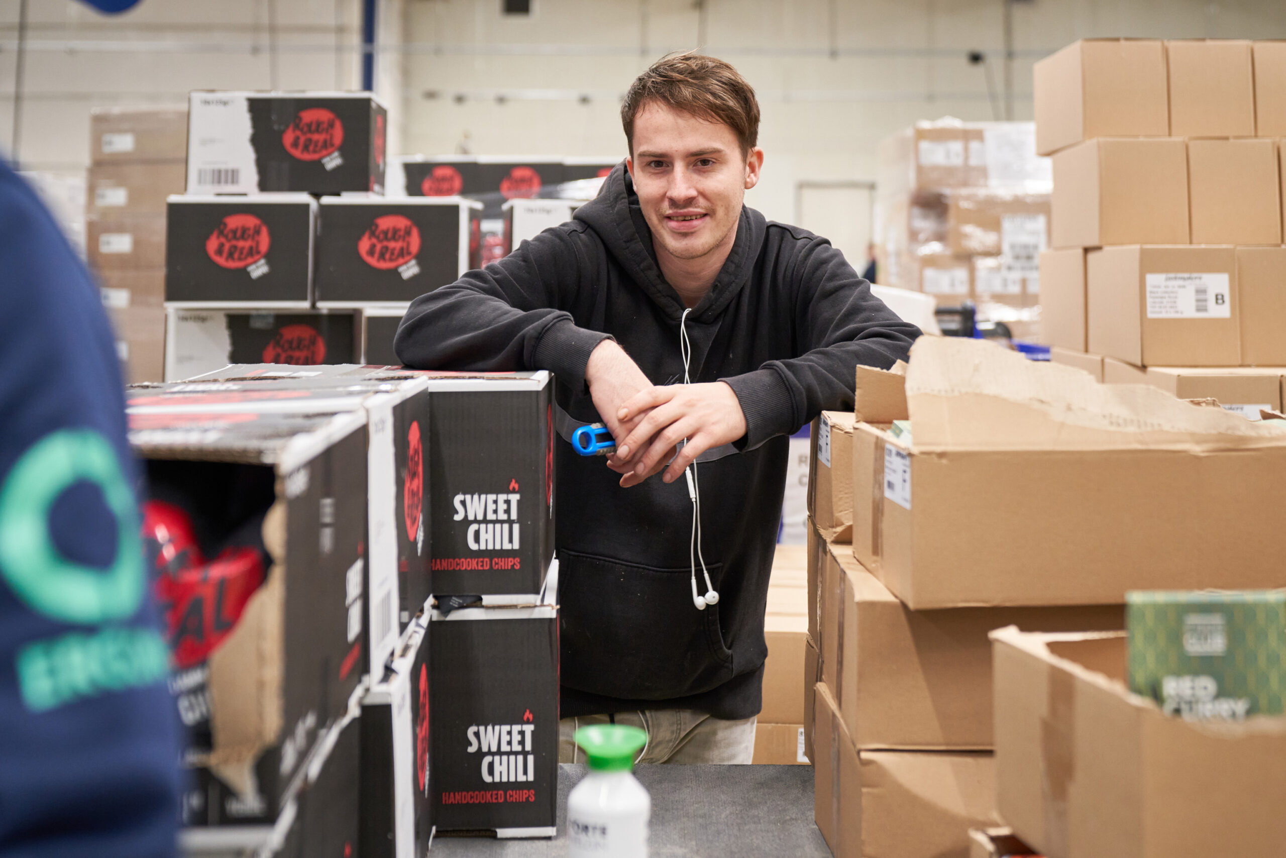 Een medewerker van Ergon Productie staat met een stanleymes in zijn handen tussen twee stapels met dozen.