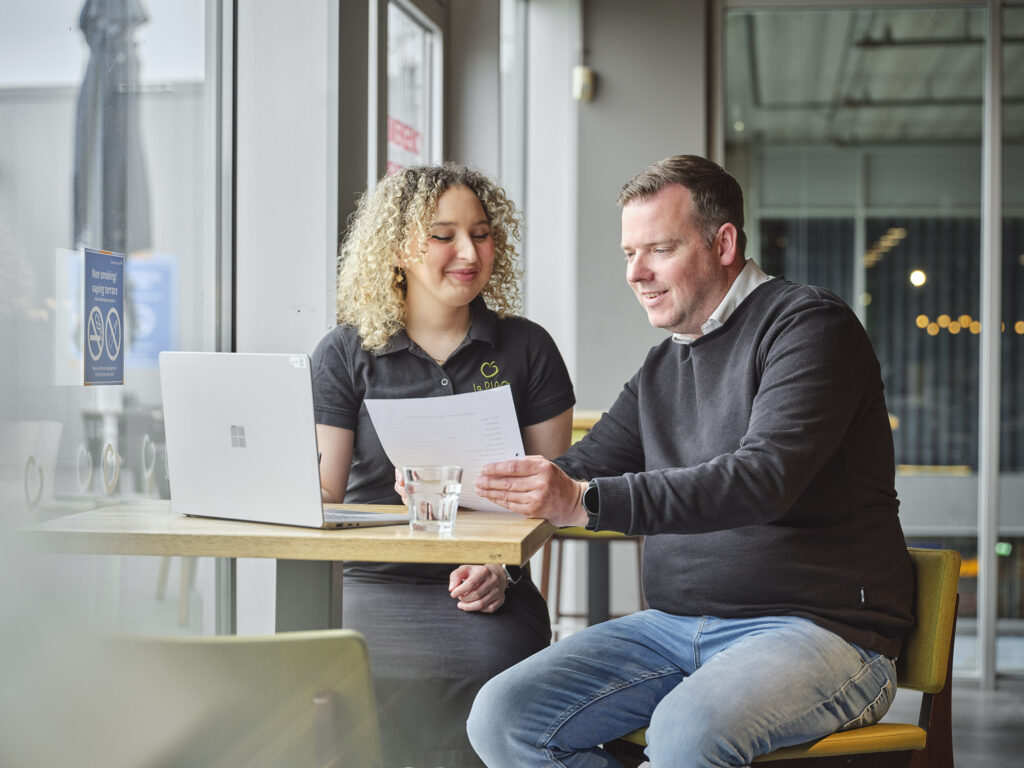 Een consulent van Ergon is in gesprek met een medewerker van La Place aan een tafel in een van de vestigingen.